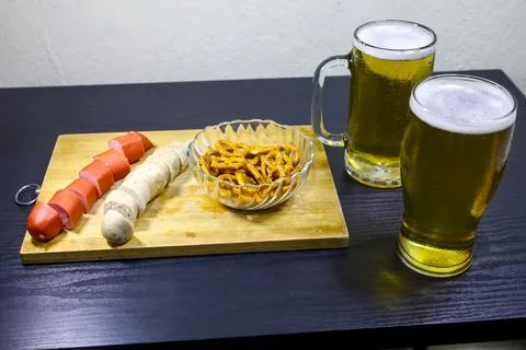 Side View Close-Up of Sliced German Sausages, Pretzels in Crystal Bowl, and.. Stock Photos