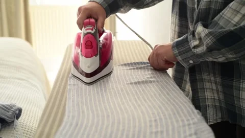 Side view close up of woman hands ironing clothes on an ironing board. 库存影片 328318948