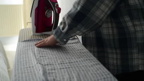 Side view close up of woman hands ironing clothes on an ironing board. Видео 328318960