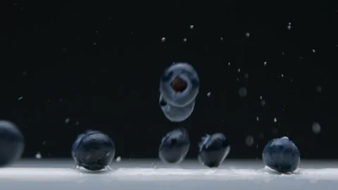 Side view closeup of blueberry falling to the empty desk with water splashes Stock Footage 131153881