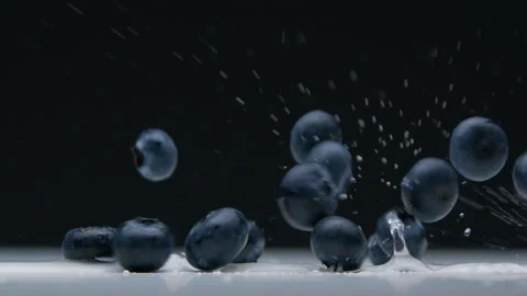 Side view closeup of blueberry falling to the desk with water splashes Stock Footage 131154321