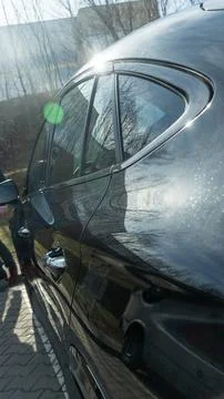 Side view closeup of luxury black polished car parked on pavement stones ou.. Stockfoto's