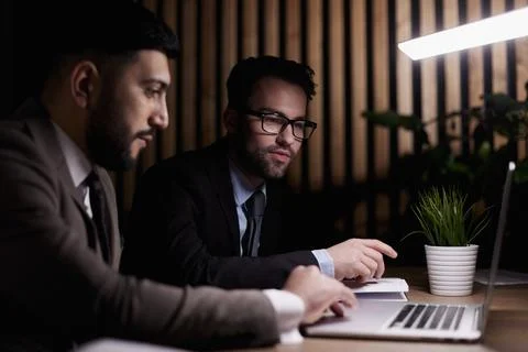 Side view of computer systems analysts using charts on computer monitors while Foto stock