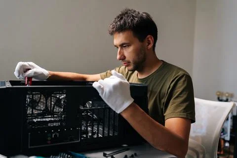 Side view of computer technician in protective gloves carefully installing Stockfoto's