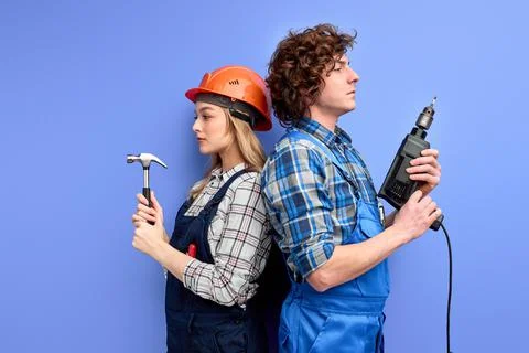 Side view on confident team of constructors builders stand back to back to each Stock Photos