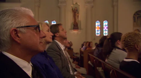 Side view of congregation kneeling in pews and bowing heads Stock Footage
