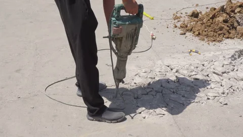 Side view of construction worker breaking concrete with electric jackhammer Stock Footage 343403524