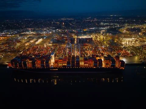 Side view of container ship lights at nigh illuminated Southampton Docks aerial Stock Photos