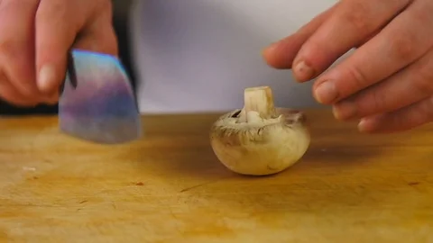 Side view cook cuts mushroom on a wooden chopping board Stock Footage 76086922