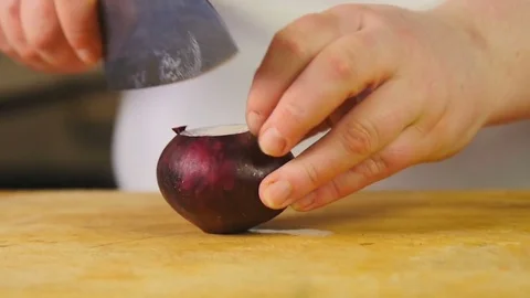 Side view cook cuts red onion into half rings on wooden chopping board Stock Footage 76086989