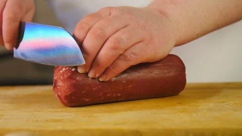 Side view cook cuts sausage into slices on a wooden chopping board Stock Footage 76087762