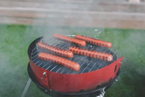 Side view of cooking process of hot dog sausages on grill Stock Photos