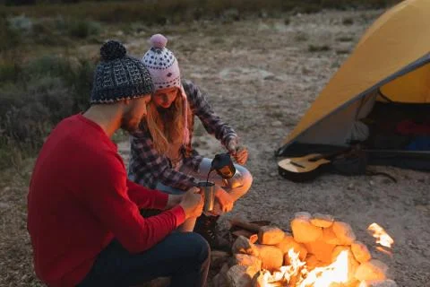 Side view of couple drinking coffee near the fire Stock Photos
