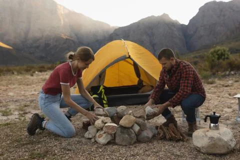 Side view of couple installing rocks for a campfire Stock Photos