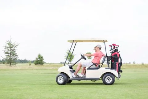 Side view of couple sitting in golf cart against clear sky Foto stock