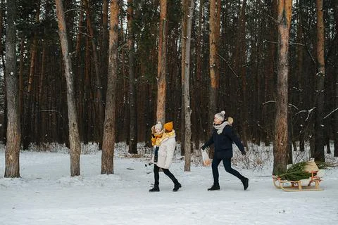 Side view of couple on a walk through the winter park with a child Stock Photos