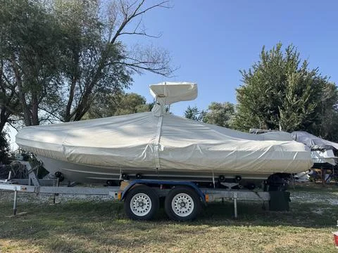 Side view of covered rigid inflatable boat parked on dual axle trailer Stock Photos
