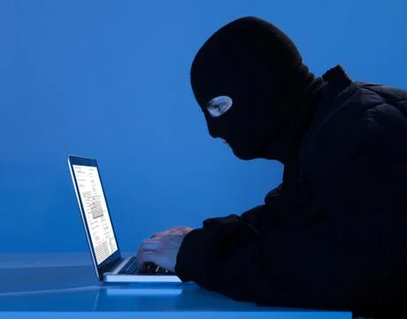 Side view of criminal using laptop to hack data at table Foto stock