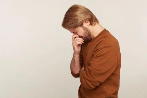 Side view of crying man bowing head wiping tears, hiding face and suffering d Stock Photos