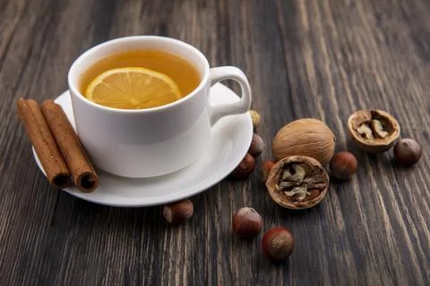 Side view of cup of hot toddy with cinnamon on saucer and nuts walnuts on w.. Stock Photos