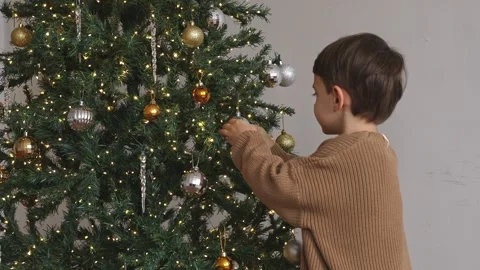 Side view of a cute little boy in warm sweater, decorating a Christmas tree Stock Footage 314066018