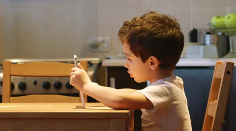 SIDE VIEW: A cute little child uses a tablet PC at a table Stock Footage 59903636