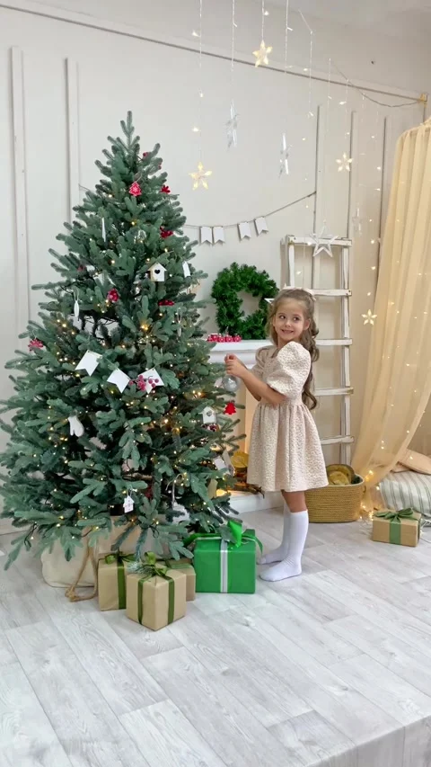 Side view cute little child girl in white dress is decorating Christmas tree  Stock Footage 288353474