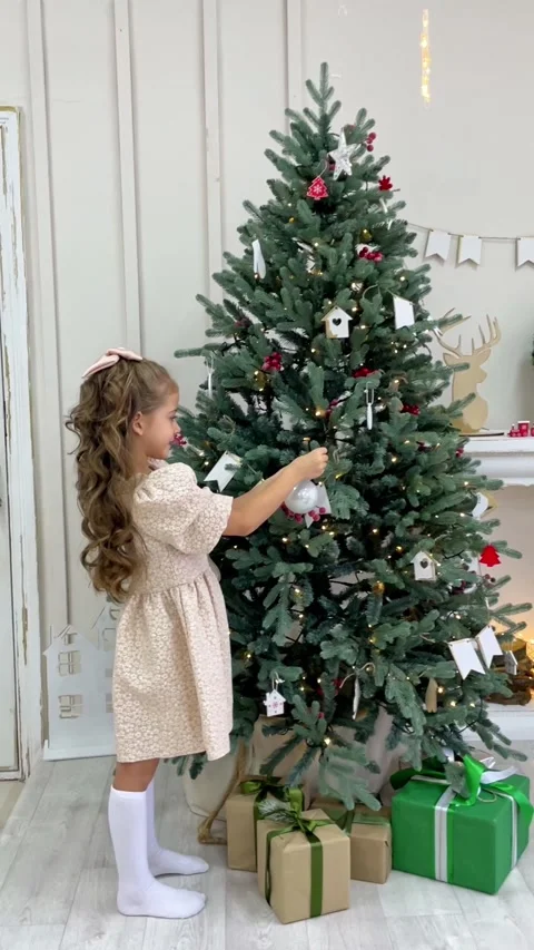 Side view cute little child girl in white dress is decorating Christmas tree  Stock Footage 288353475