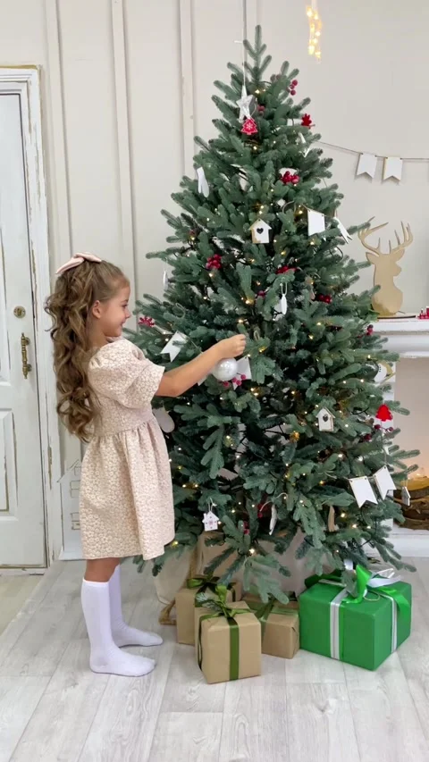 Side view cute little child girl in white dress is decorating Christmas tree  Stock Footage 288353494