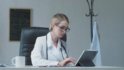 Side view of a cute young doctor in a white coat, working at a tablet with a  Stock Footage 135764990