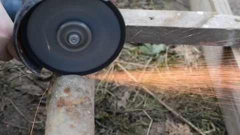 Side view of cutting old rusted iron pipe with an angle grinder Stock Footage 74542380