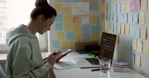 Side view of dark-haired freelancer using modern smartphone while sitting at Stock Footage 148565448