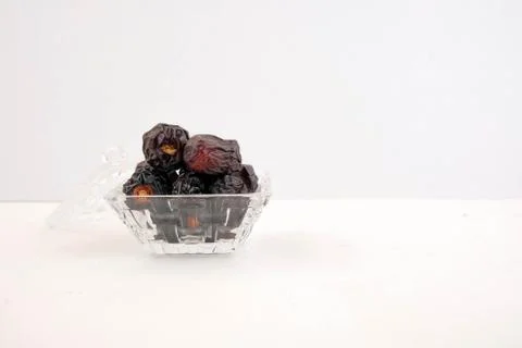 Side view of dates on glassware over white. Stock Photos