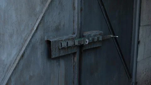 Side view of deadbolt of an old gray metal gate. The bolt is closed. Stock Photos