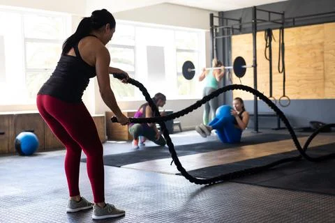 Side view of dedicated caucasian young woman exercising with battle ropes in Fotos Stock