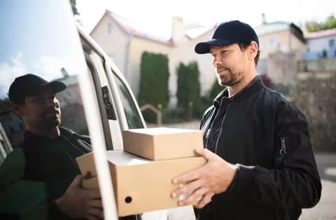 Side view of delivery man courier delivering parcel box in town. 写真素材