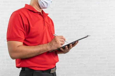 Side view. Delivery man worker wearing surgical mask in red uniform isolate.. Stock Photos
