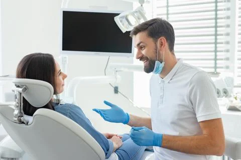 Side view of dentist advicing and gesturing to patient in modern clinic Stock Photos
