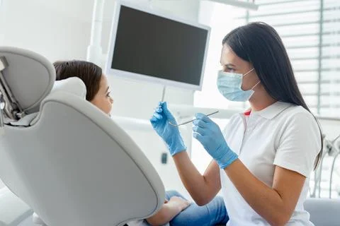 Side view of dentist in mask examining teeth of small client in the hospital Stock Photos