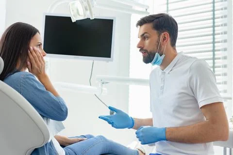 Side view of dentist talking to patient is upset of pain in dentist office Stock Photos