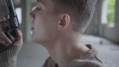 Side view of a depressed crazy young man holding revolver in hands, slowly Stock Footage 113476514