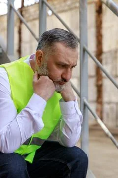 Side view. Depressed foreman sitting outdoors on stairs and feeling tired after Stock Photos