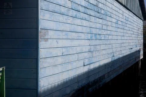 A side-view detail of a rustic blue wooden building on a waterfront Stock Photos