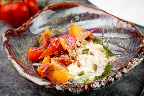 Side view of a dish of baked persimmons, colored peppers, rice and seeds Stock Photos