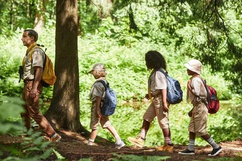 Side view at diverse group of scouts hiking lit by sunlight Stock Photos