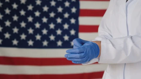 Side view of Doctor wears protective gloves against American flag Stock Footage 129331513