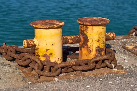 Side View of A double bitt mooring bollard with a heavy chain around it. Stock Photos