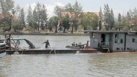 Side view of a dredging boat on Kampot river pumping riverbed sand Stock Footage 186590043