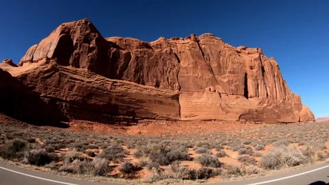 A Side View Driving Past a Massive Red Rock Cliff Face in Arches Natioanl Park Video stock 261987342
