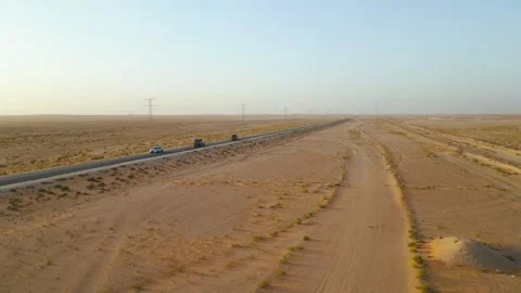 Side View Drone Shot of Two 4x4 Vehicles Driving on Desert Road at Sunrise Stock Footage 341517237